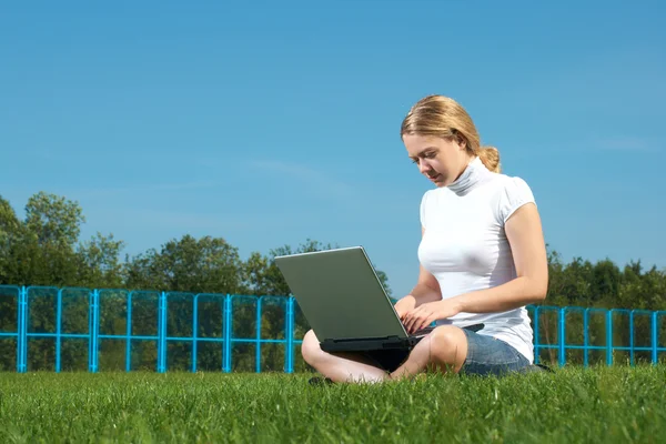 The girl with laptop on a green lawn — Stock Photo, Image