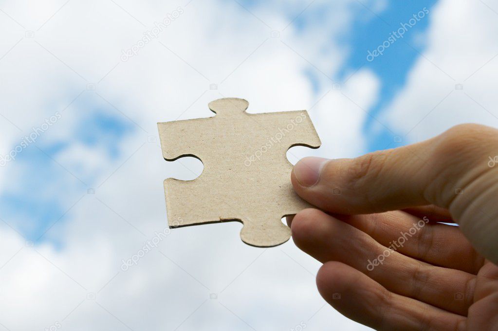 The hand holds puzzle on a background of the sky