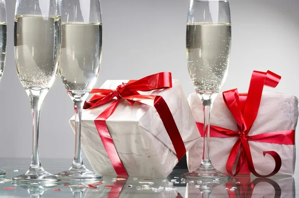 Бокалы шампанского, подарки с красными лентами и бантами — стоковое фото