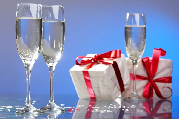 Bicchieri di champagne, regali con nastri rossi e fiocchi — Foto Stock