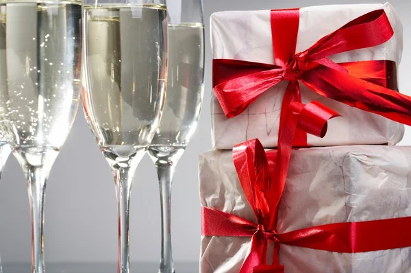 stock image Glasses of champagne, gifts with red tapes and bows