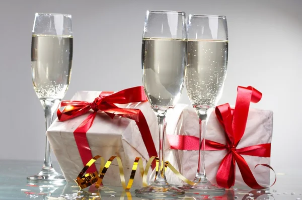 Pohár pezsgő, ajándékok, vörös szalagok és íjak — Stock Fotó
