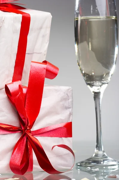 stock image Glasses of champagne, gifts with red tapes and bows