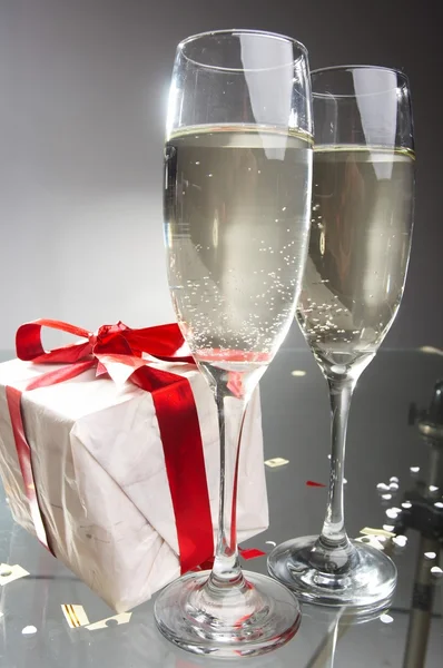 Okulary szampana, prezenty z czerwone taśmy i łuki — Zdjęcie stockowe