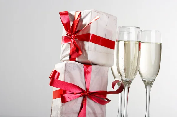 stock image Glasses of champagne, gifts with red tapes and bows