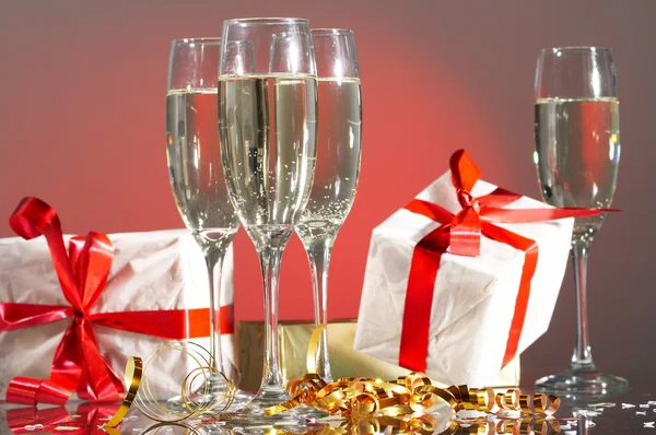 Glazen van champagne, geschenken met rode tapes en strikken — Stockfoto