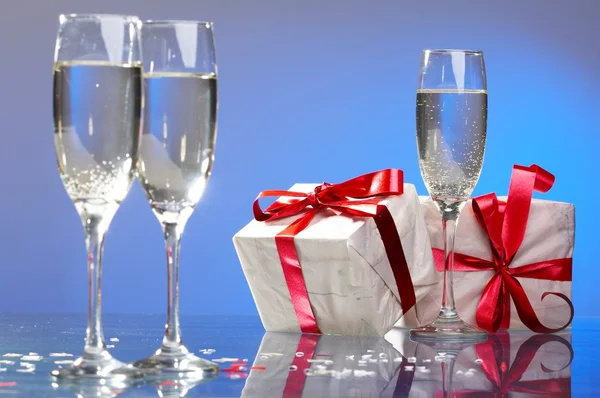 Glasses of champagne, gifts with red tapes and bows Royalty Free Stock Photos