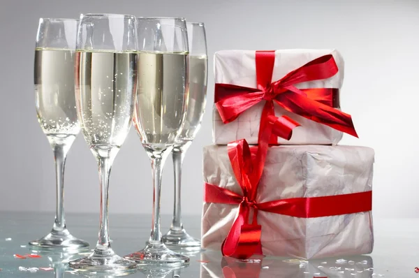 Copas de champán, regalos con cintas rojas y arcos — Foto de Stock