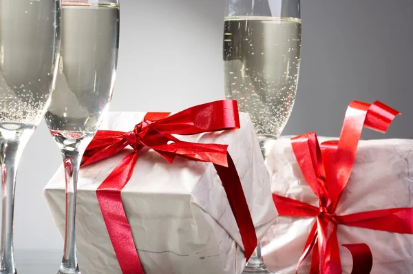 stock image Glasses of champagne, gifts with red tapes and bows