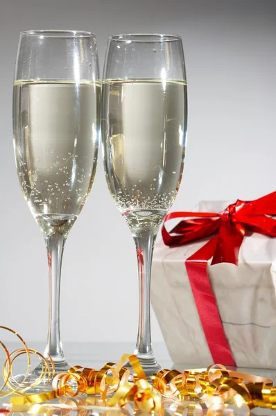 Briller af champagne, gaver med røde bånd og buer - Stock-foto