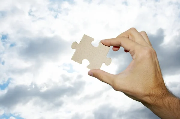 stock image The hand holds puzzle on a background of the sky