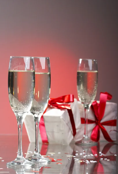 Бокалы шампанского, подарки с красными лентами и бантами — стоковое фото