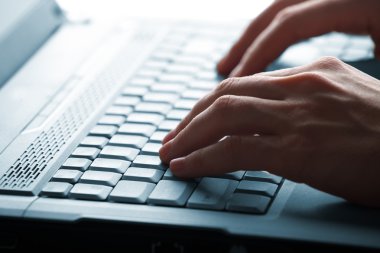 Erkek eller dizüstü bilgisayarda yazıyor.