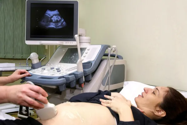 Mujer embarazada y médico de la mano con equipo de ultrasonido — Foto de Stock
