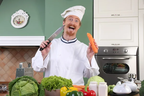 Grappige jonge chef-kok voorbereiding lunch in keuken — Stockfoto