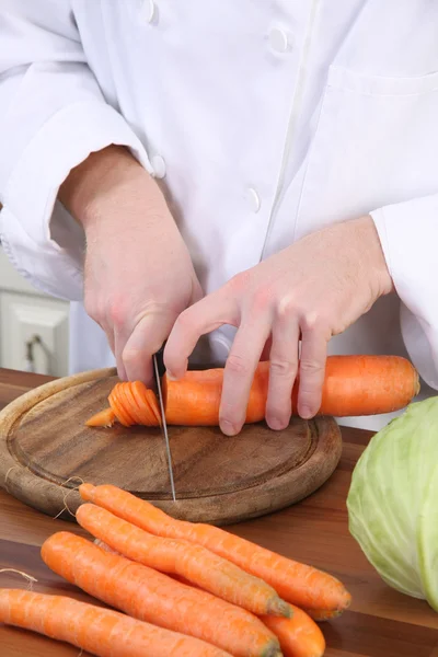 Koch bereitet Mittagessen zu und schneidet Karotten mit Messer — Stockfoto