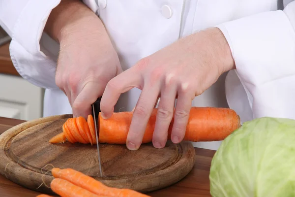 Chef preparing lunch and cutting carrot with knife — Stock Photo, Image