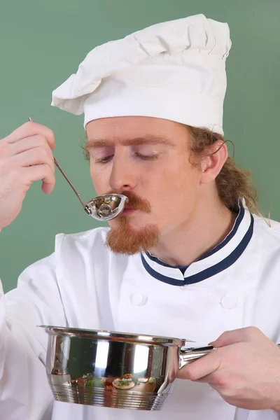 Jovem Chef degustação de alimentos com uma colher de sopa — Fotografia de Stock