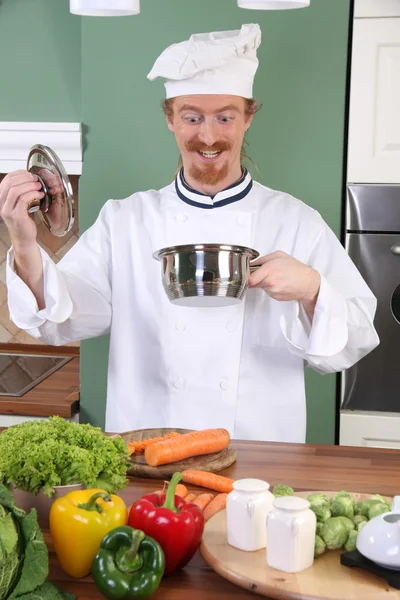 Grappige jonge chef-kok vreemd kijken naar pot — Stockfoto
