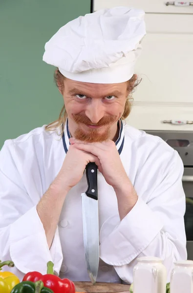 Engraçado jovem chef com uma faca na cozinha — Fotografia de Stock