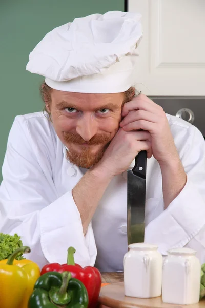 Забавный молодой шеф-повар с ножом на кухне — стоковое фото