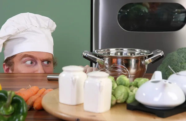 Legrační mladý kuchař divně při pohledu na hrnec — Stock fotografie