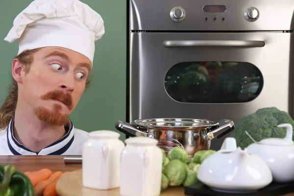 Grappige jonge chef-kok vreemd kijken naar pot — Stockfoto