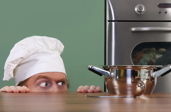 Funny young chef strange looking at pot — Stock Photo, Image