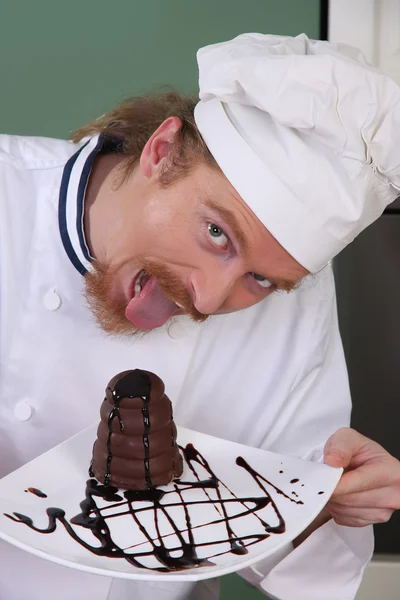 Забавный молодой шеф-повар ест кусок торта — стоковое фото