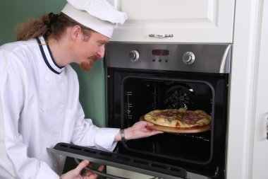 Young chef prepared italian pizza in kitchen clipart