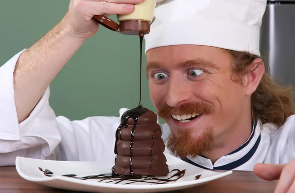 Смішний молодий шеф-кухар додав шоколадний соус на шматочок торта — стокове фото