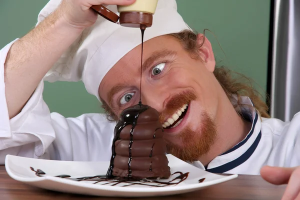 Grappige jonge chef-kok toegevoegd chocoladesaus op fluitje van een cent — Stockfoto