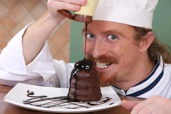 Drôle de jeune chef a ajouté de la sauce au chocolat au morceau de gâteau — Photo