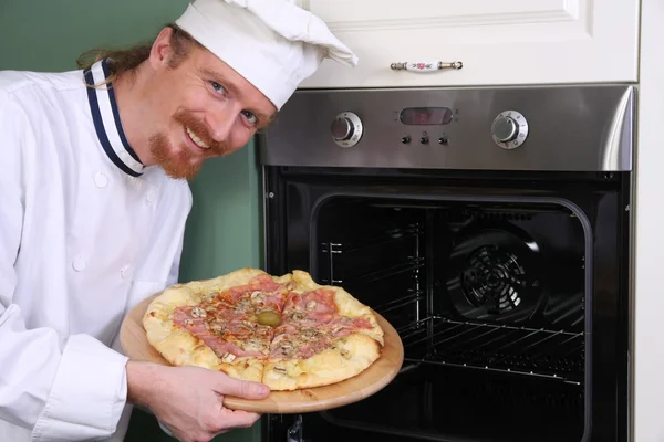Jonge chef-kok met Italiaanse pizza in keuken — Stockfoto