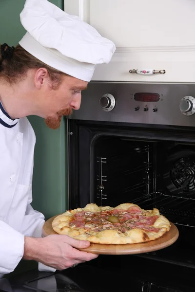 Молодой шеф-повар приготовил итальянскую пиццу на кухне — стоковое фото