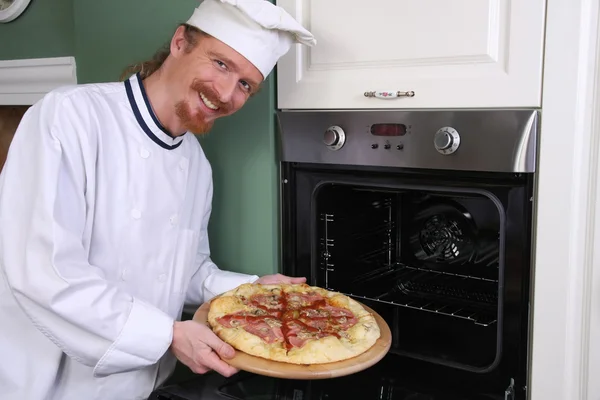 Joven chef con pizza italiana en la cocina — Foto de Stock