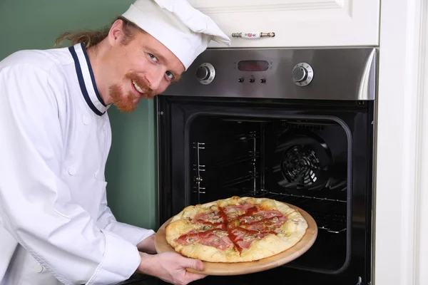 Молодой шеф-повар с итальянской пиццей на кухне — стоковое фото