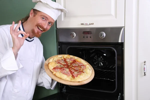 Young chef with italian pizza in kitchen — Stock Photo, Image