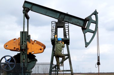 Oil worker climbs to the pumpjack clipart