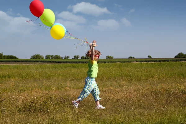Маленькая девочка бегает с воздушными шарами — стоковое фото