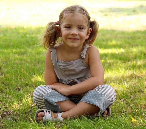 Dziewczynka siedzi na trawie — Zdjęcie stockowe