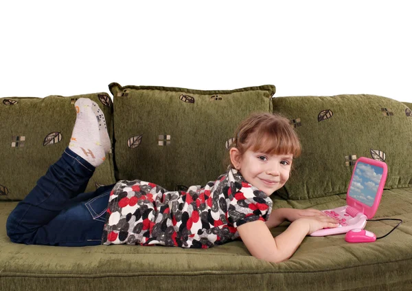 Маленькая девочка лежит на кровати с ноутбуком — стоковое фото