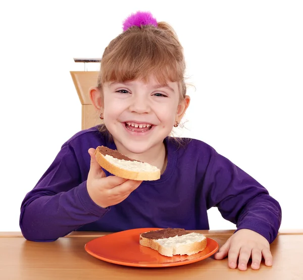 Happy little girl eats bread with chocolate — Stock Photo, Image