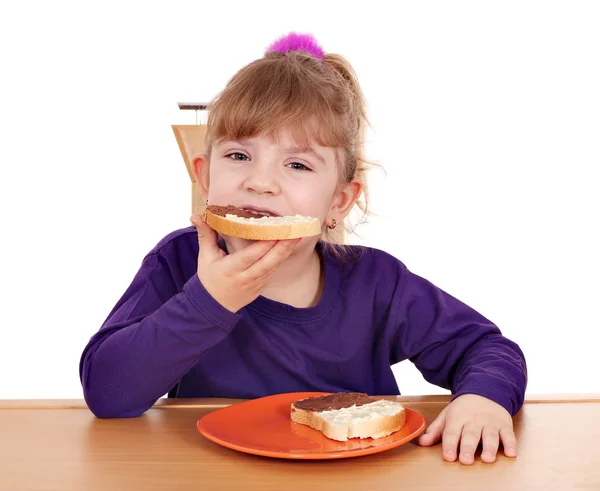 Hungry little girl eats bread with chocolate cream — Stock Photo, Image