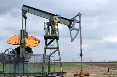 Oil worker standing at pump jack clipart