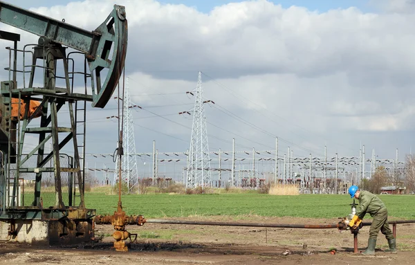 Oljefält med pump jack och arbetare — Stockfoto