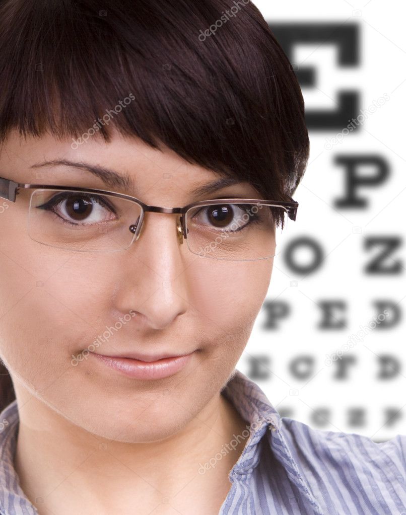 Woman with glasses, eye chart in background. At the Optician