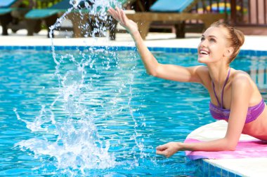 Happy woman splashing water in pool clipart