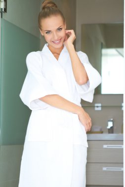 Relaxed woman standing in white bathrobe clipart