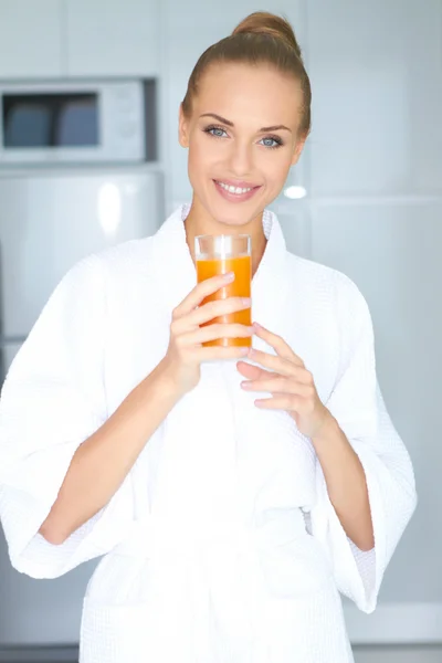 Mulher de roupão de banho bebendo suco de laranja — Fotografia de Stock
